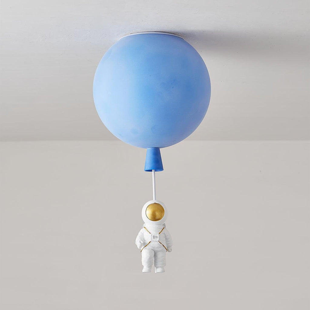 Blue Clérachic balloon ceiling light, unlit, with a matching cap and a seated astronaut hanging below.