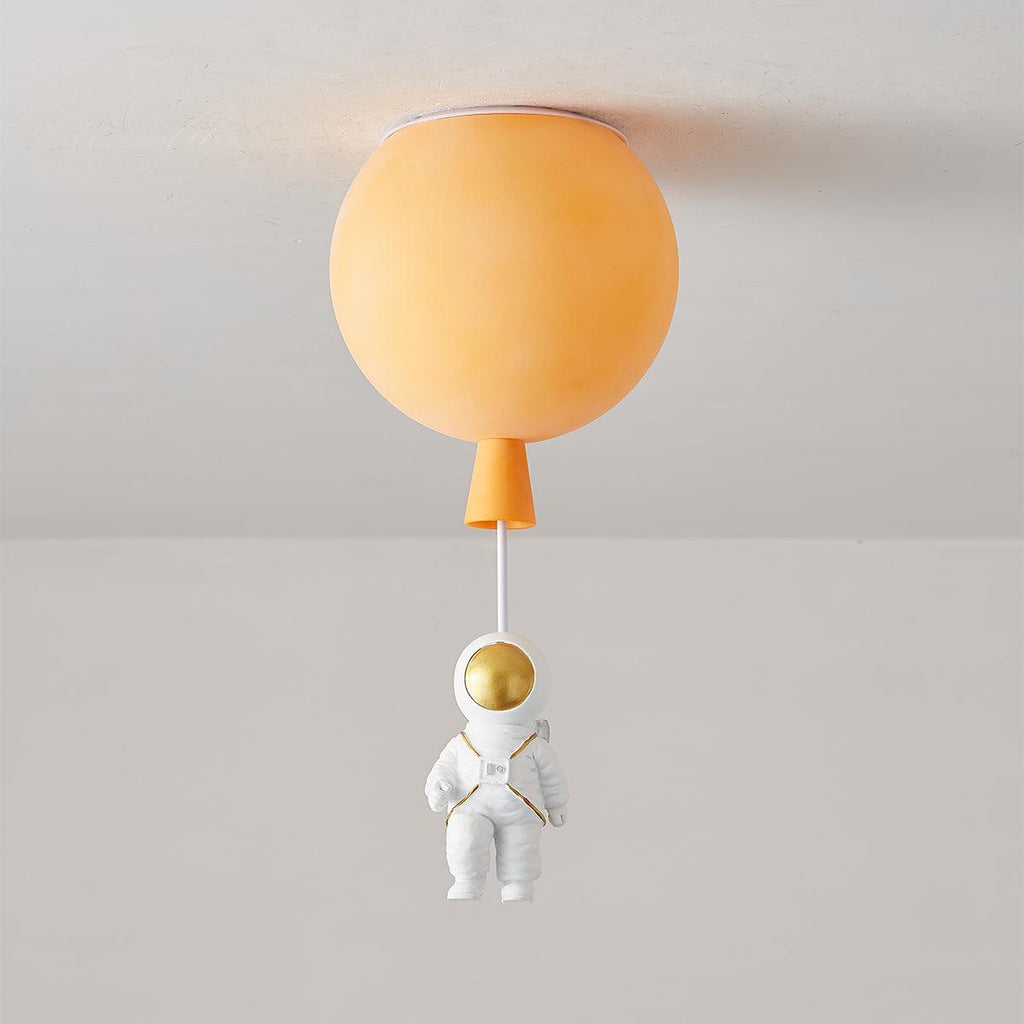 Orange Clérachic balloon ceiling light, unlit, with an orange cap and a seated astronaut below.