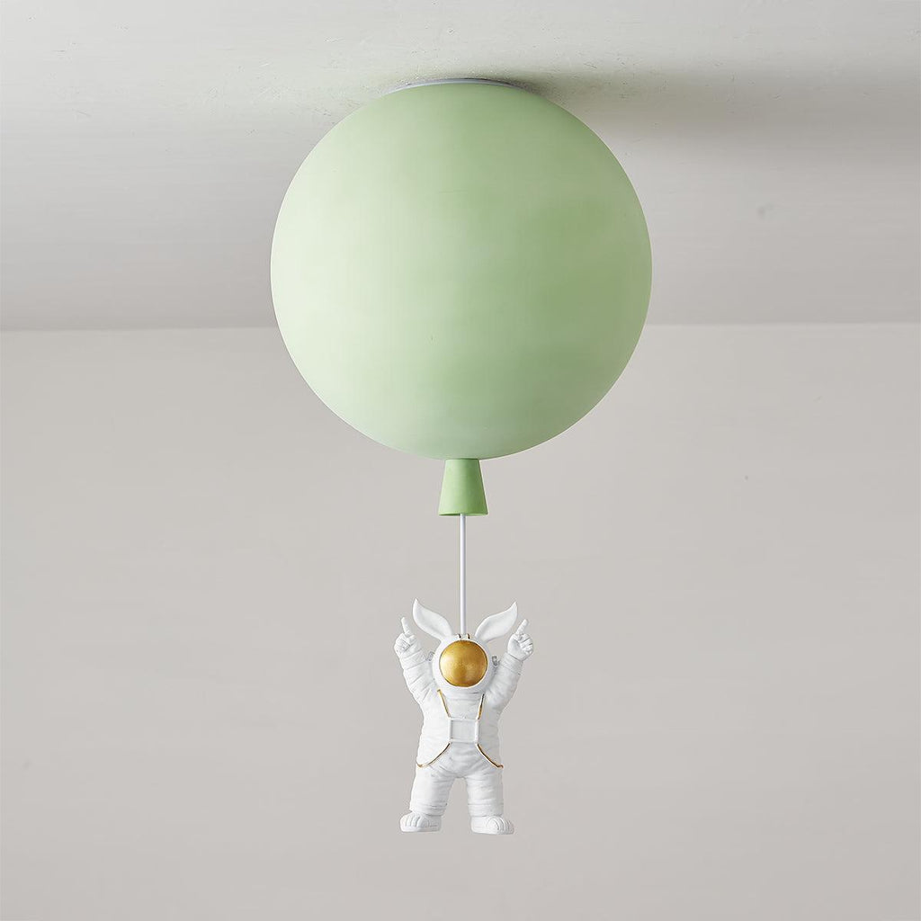 Green Clérachic balloon ceiling light, unlit, with a green cap and an astronaut with raised arms hanging below.