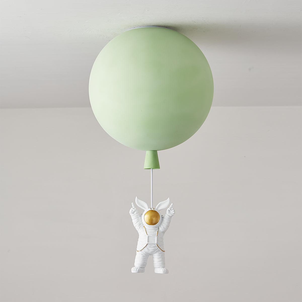 Green Clérachic balloon ceiling light, unlit, with a green cap and an astronaut with raised arms hanging below.
