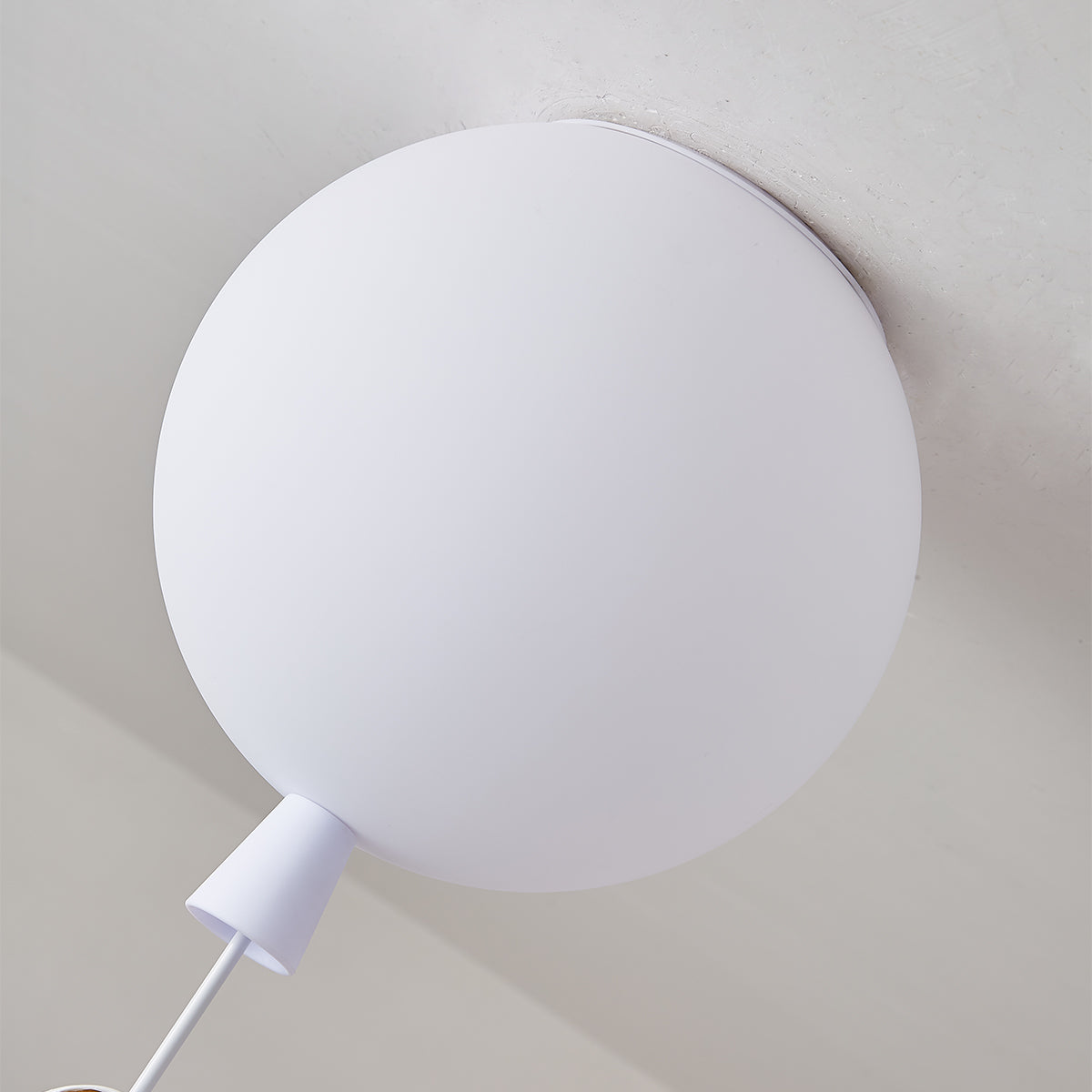Close view of the frosted white balloon diffuser, the ceiling mount and the cap of this Clérachic ceiling light.