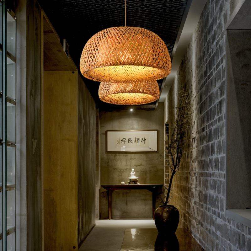 Clérachic woven bamboo dome pendants stacked in two tiers above a corridor room with a brick wall and a dark console table.
