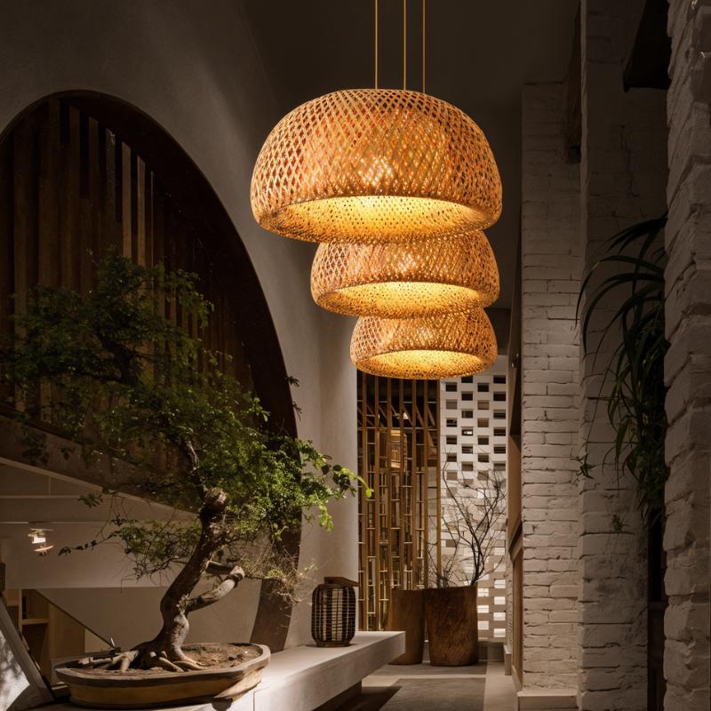 Clérachic three woven bamboo dome pendants at staggered heights, glowing warm in a room with a bonsai and white brick wall.