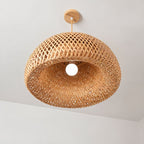 Looking up at a Clérachic woven bamboo bowl pendant: an open lattice shade, a bare round bulb and a pale wooden ceiling canopy.
