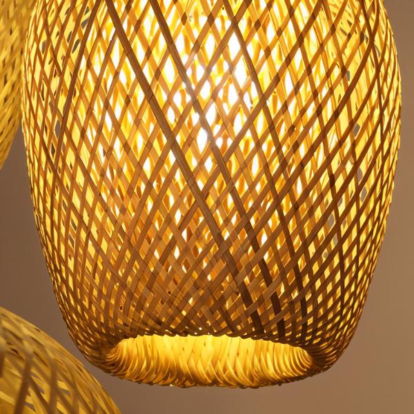 Close up of the Clérachic woven bamboo cocoon pendant, its criss-cross lattice glowing amber from the bulb inside the shade.