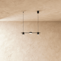 Another angle of the Clérachic black three-head pendant bar, cylindrical heads glowing warm white on thin support cables.
