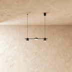 Another angle of the Clérachic black three-head pendant bar, cylindrical heads glowing warm white on thin support cables.