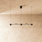 The Clérachic black five-head linear pendant bar, its round LED heads glowing warm white in a row beneath the ceiling.
