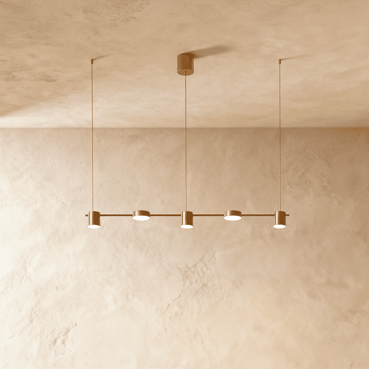 Angled view of the Clérachic gold five-head pendant bar, cylindrical heads glowing warm white beneath a textured ceiling.