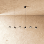 The Clérachic black six-head linear pendant bar, its round LED heads glowing warm white in a long row overhead.
