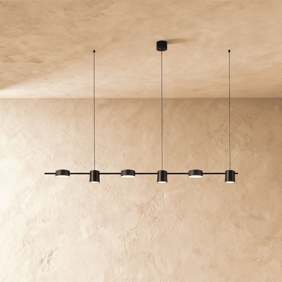 Another angle of the Clérachic black six-head pendant bar, cylindrical heads glowing warm white on thin support cables.