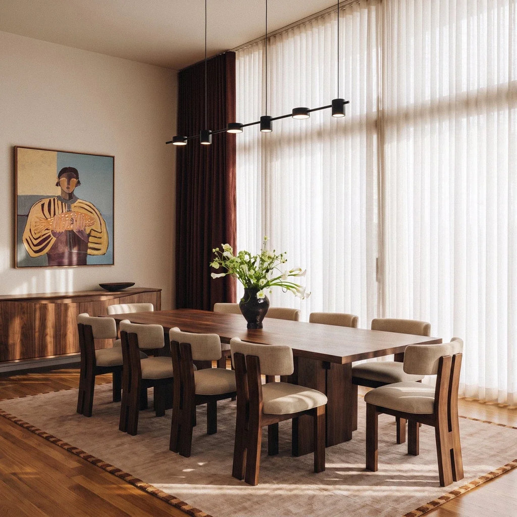 The Clérachic black six-head pendant bar glowing warm white above a long walnut dining table seating ten.
