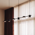 The Clérachic black six-head pendant bar glowing warm white beside sheer curtains and a rust-toned drape.