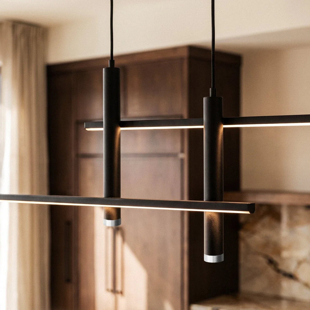 Close-up of a lit Clérachic black bar pendant light, its dual LED strips glowing warm above dark wood kitchen cabinets.