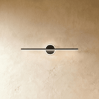 Clérachic longer black bar wall light with a lit ring backplate, mounted on a textured, warm cream plaster wall.