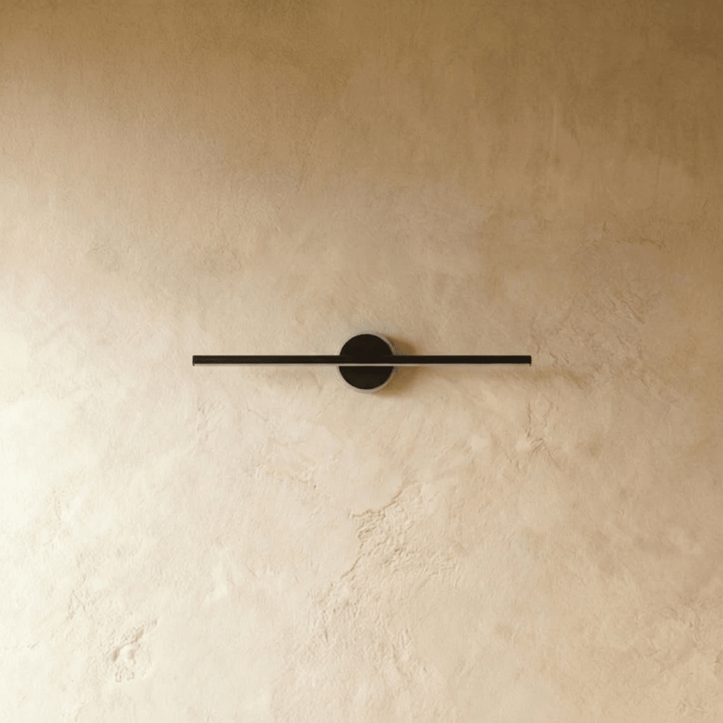 Clérachic black bar wall light with the light switched off, round black backplate on a warm limewash wall.