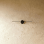 Clérachic black bar wall light with the light switched off, round black backplate on a warm limewash wall.