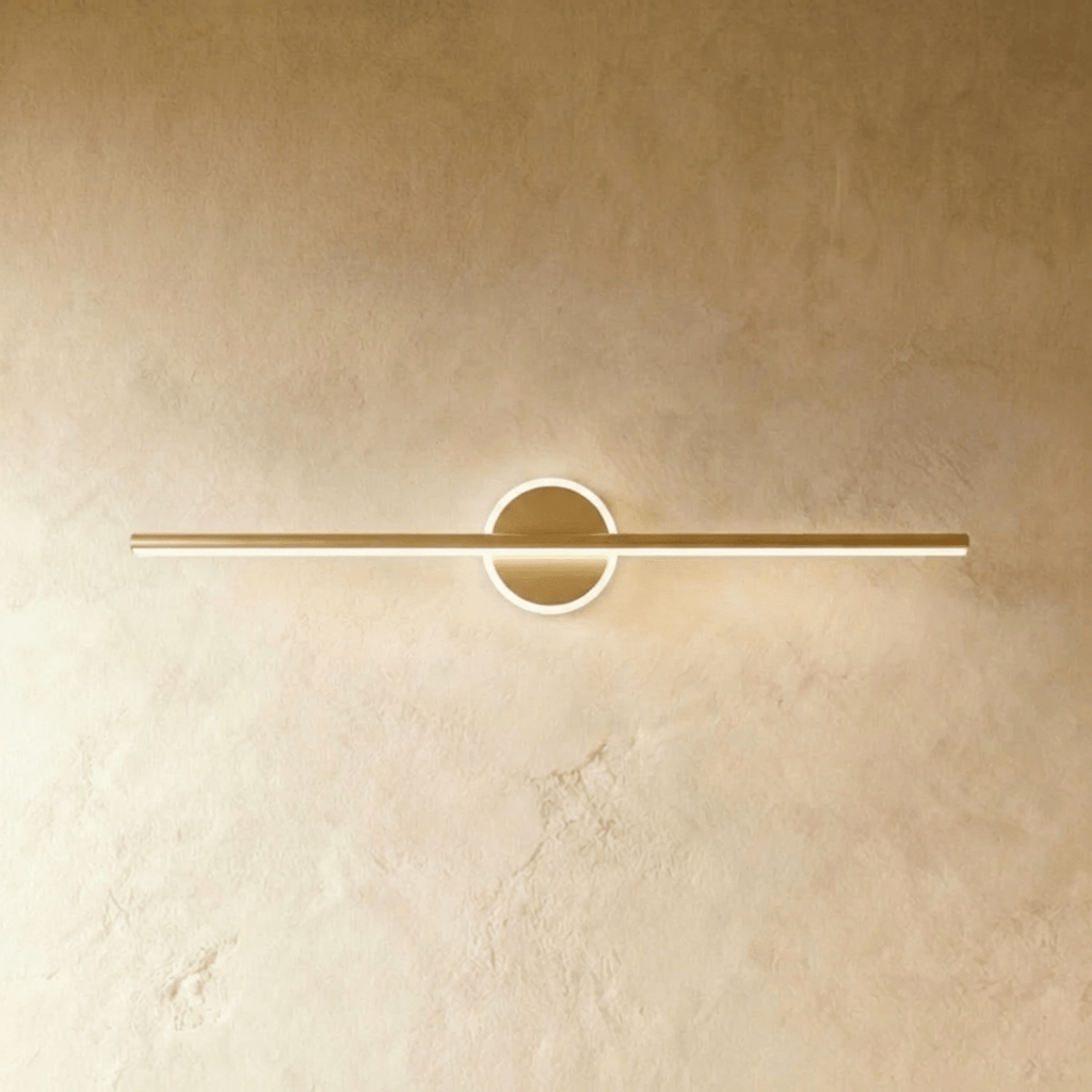 Clérachic longest gold bar wall light with a lit ring backplate, mounted on a warm cream limewash wall.