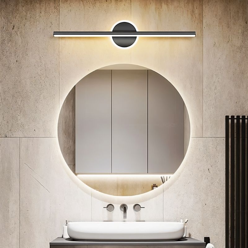 Clérachic black bar wall light above a backlit round bathroom mirror, with a pale tiled wall and a white basin.