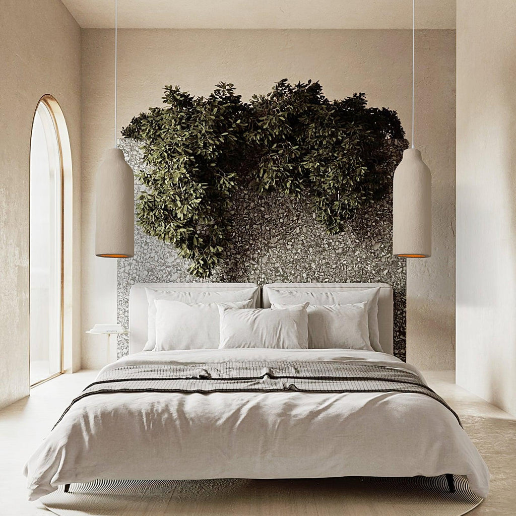 Two slim beige Clérachic pendant lights hanging either side of a bed with a leafy green headboard wall and an arched window.