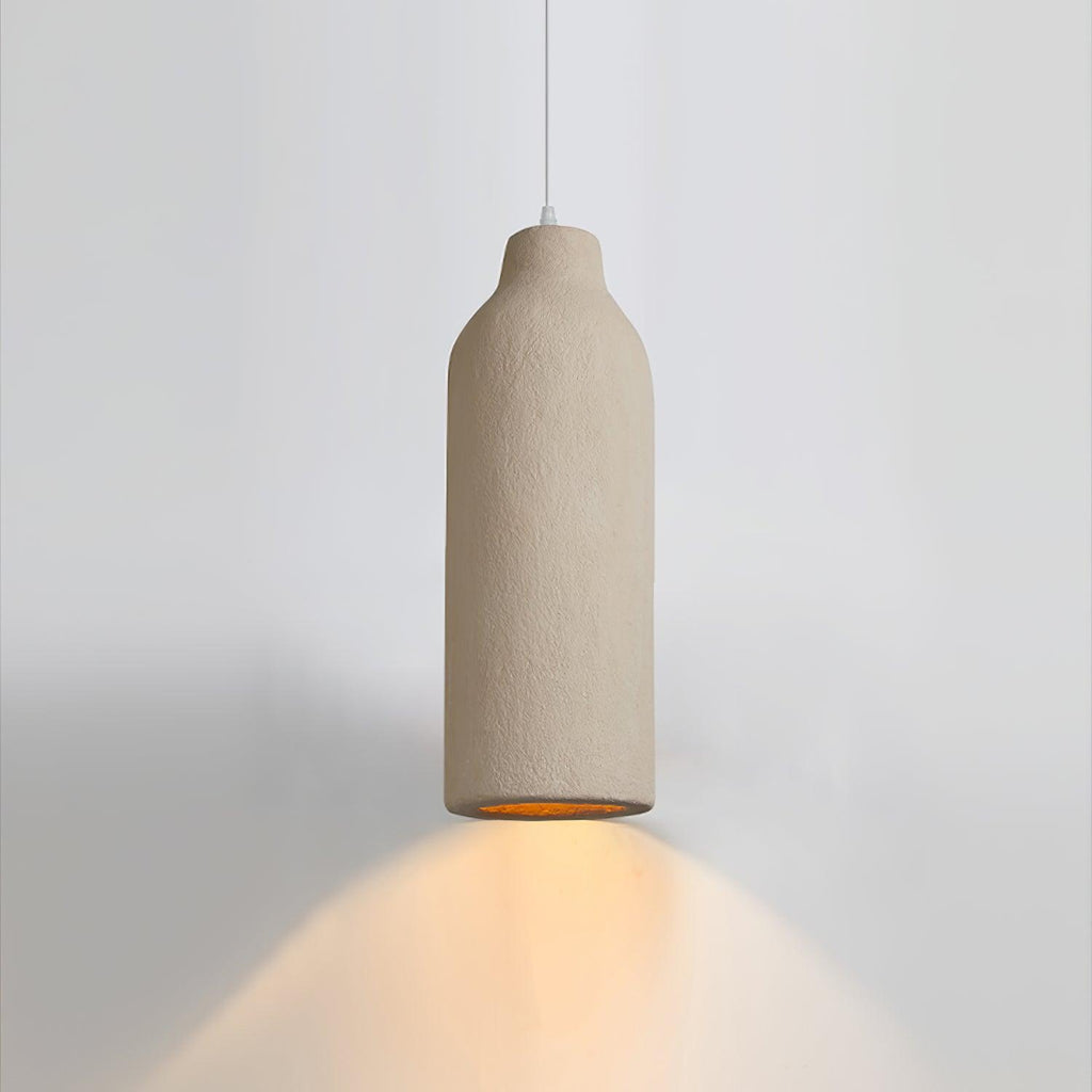 This Clérachic pendant light in a slim bottle shape throws a warm cone of amber light down onto a pale grey wall.
