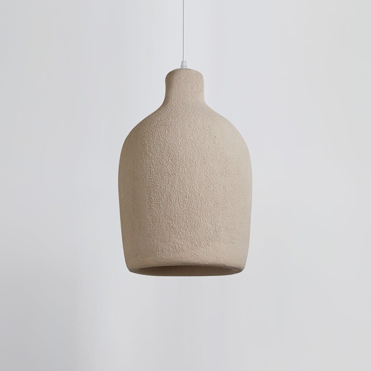 A wide, rounded Clérachic pendant light in a rough beige finish, seen side-on against a pale grey backdrop.