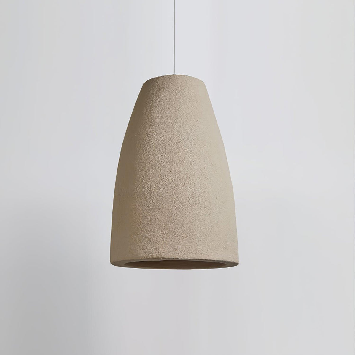 A tapered, bell-shaped Clérachic pendant light in a rough beige finish, on a pale grey backdrop, with its white cable above.