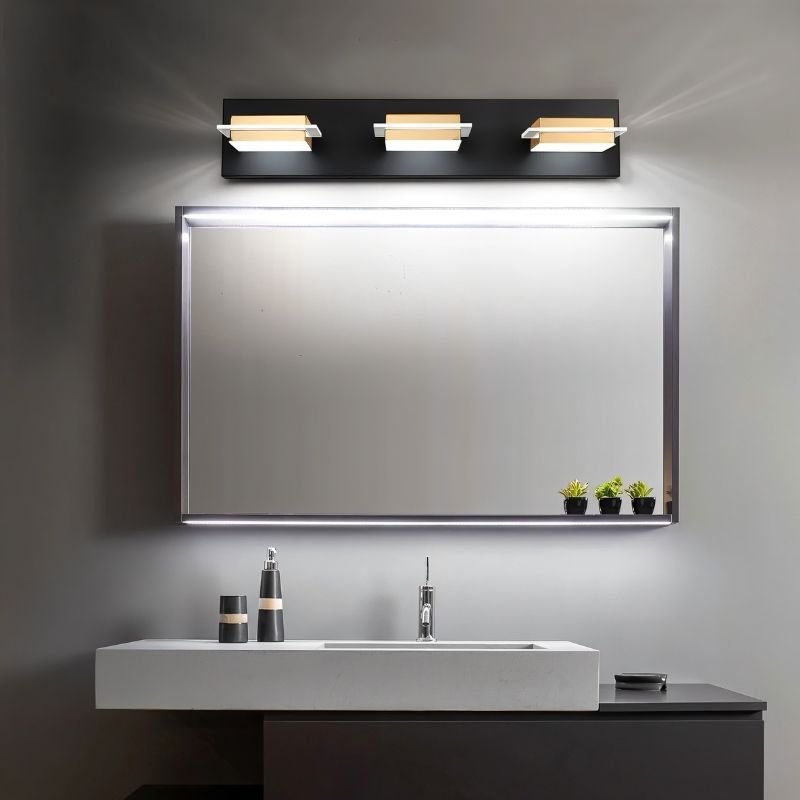 Clérachic three-head black wall bar with gold-toned bands and frosted diffusers above a framed bathroom mirror and stone basin.