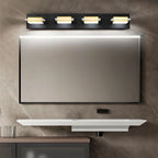 Clérachic four-head black wall bar with gold-toned bands and frosted diffusers, centred above a black-framed bathroom vanity mirror.