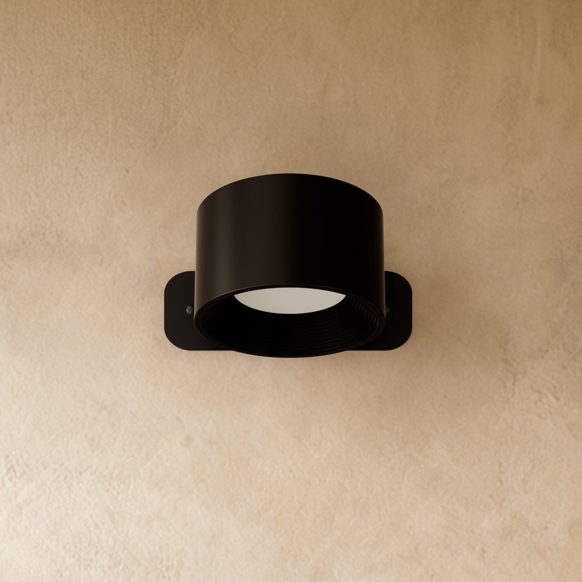 Clérachic compact black round wall lamp with a short drum head, switched off on a warm limewashed wall.
