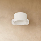 Clérachic compact white round wall lamp with a short drum head, switched off on a warm limewashed wall.