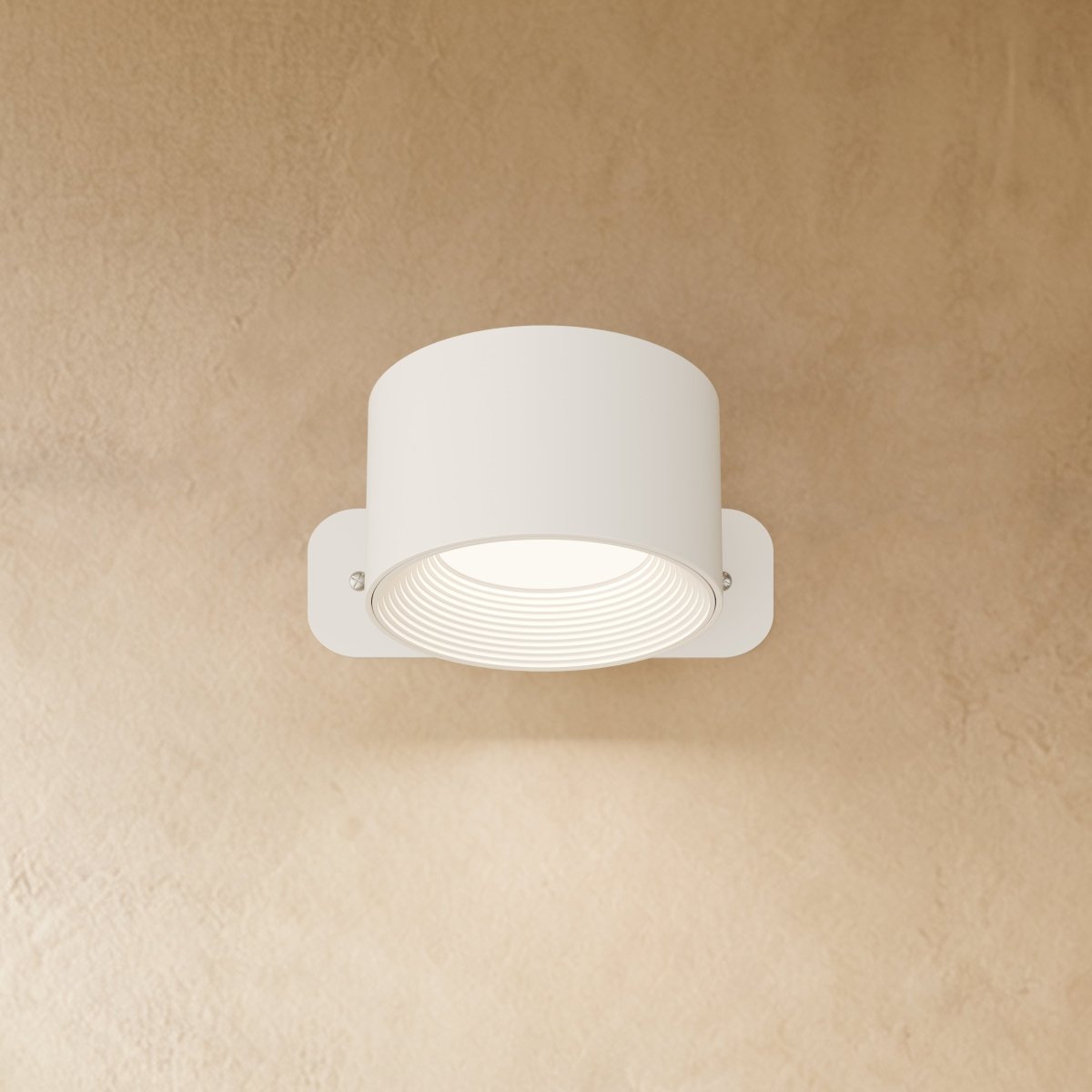 Clérachic compact white round wall lamp with a short drum head, lit, its ribbed inner ring glowing soft white.