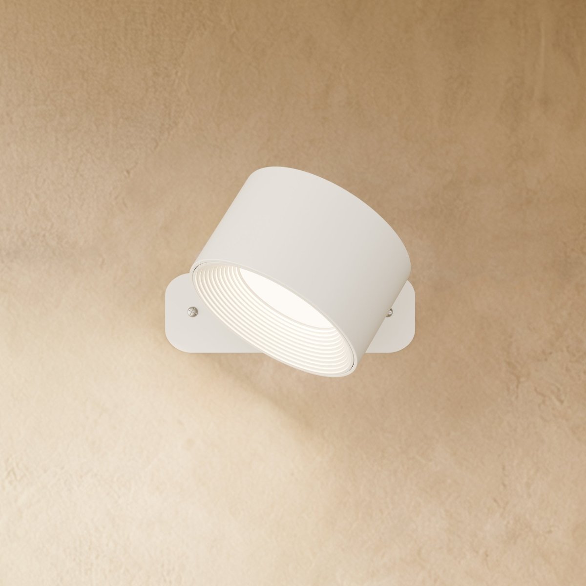Clérachic white wall lamp with the drum head angled down on its pivot, a ribbed inner ring glowing white.