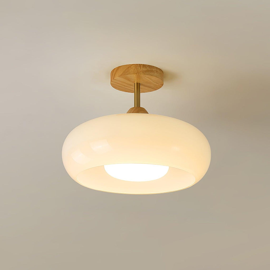 Clérachic Bauhaus glass disc ceiling light in cream opal white, glowing softly beneath a natural wood ceiling canopy.