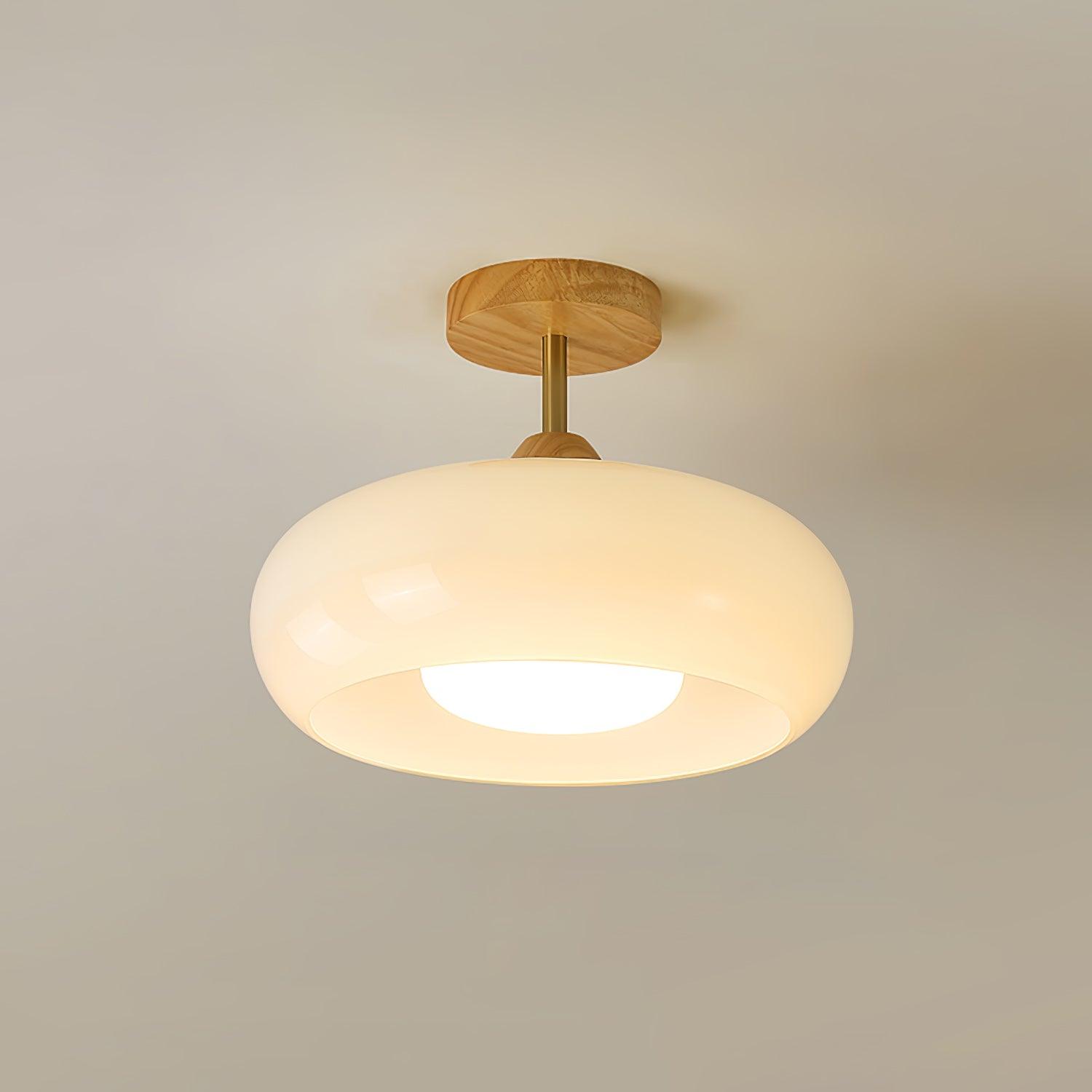 Clérachic Bauhaus glass disc ceiling light in cream opal white, glowing softly beneath a natural wood ceiling canopy.