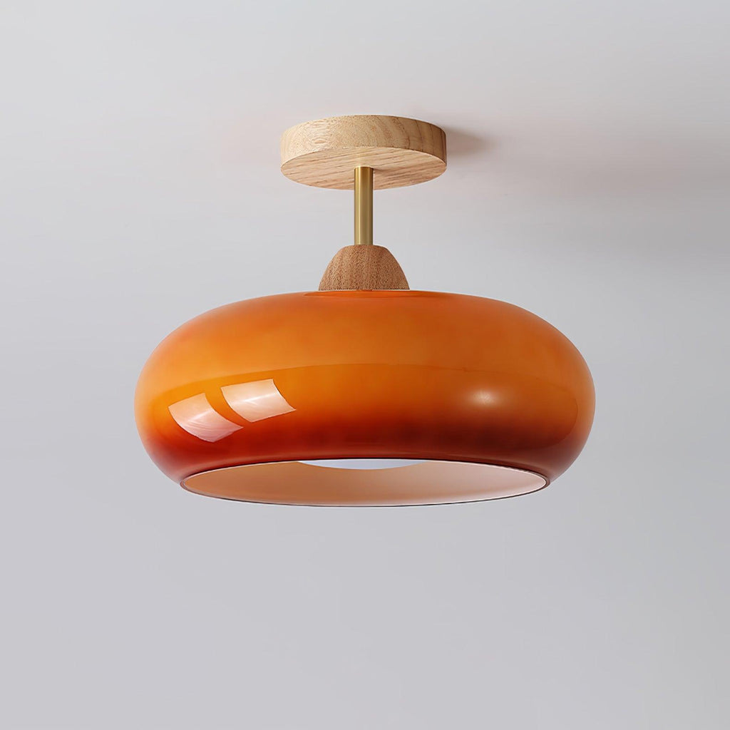 Clérachic Bauhaus glass disc ceiling light in deep amber glass, the highlight running along its rounded doughnut rim.