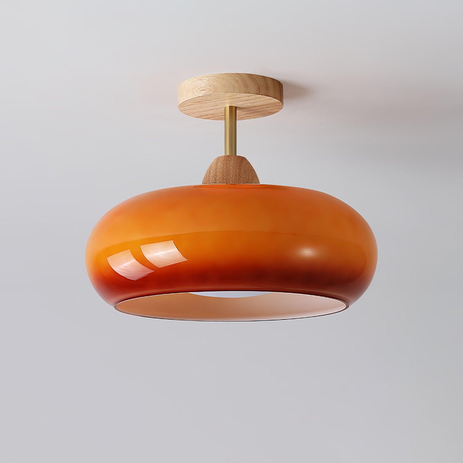 Clérachic Bauhaus glass disc ceiling light in deep amber glass, the highlight running along its rounded doughnut rim.