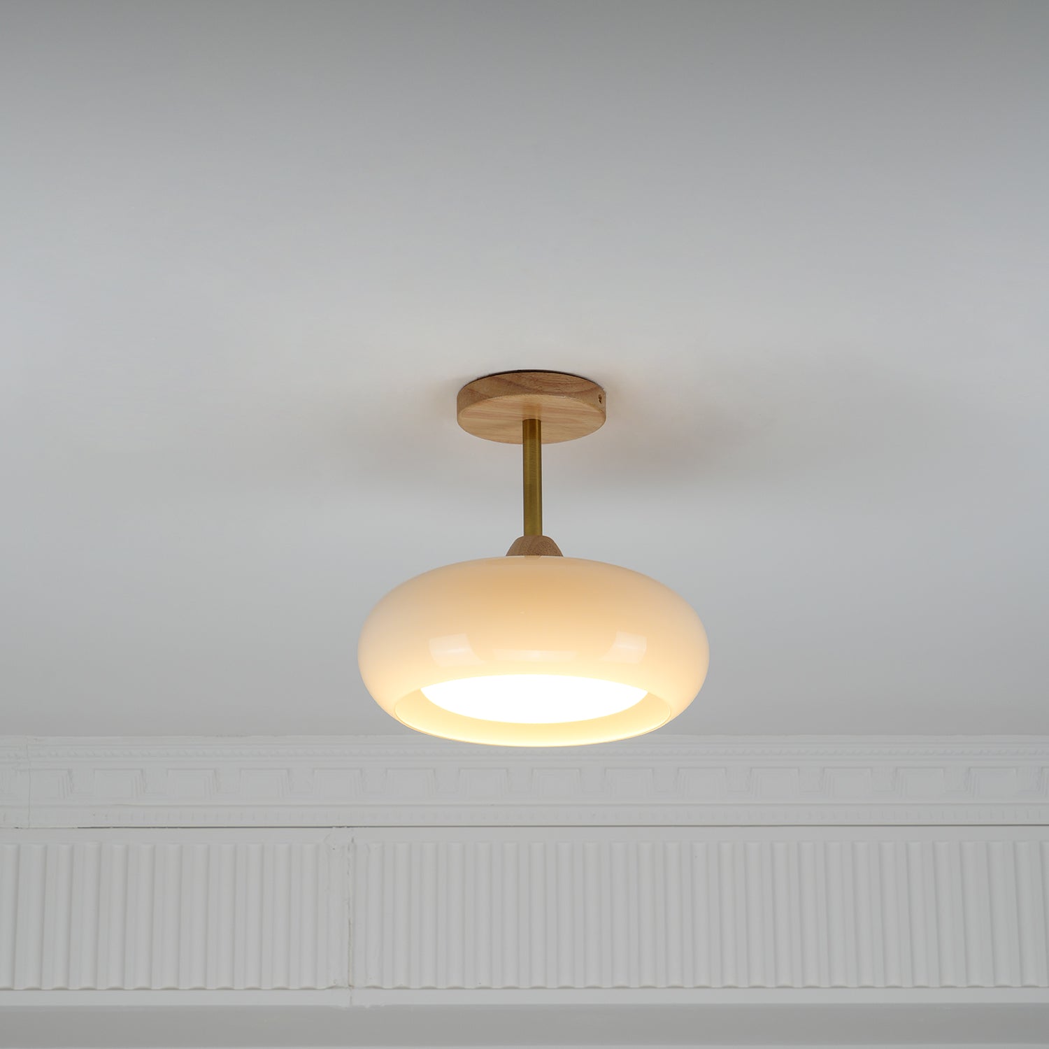 Clérachic Bauhaus glass disc ceiling light in cream opal, lit on a white ceiling above a moulded plaster cornice.