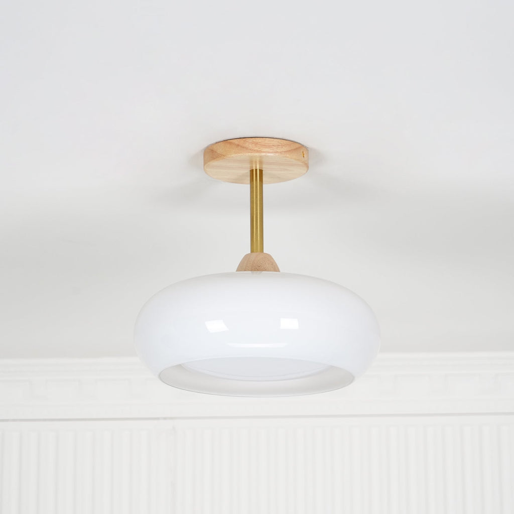 Front view of the Clérachic Bauhaus glass disc ceiling light unlit, its slim brass stem clear against a white wall.