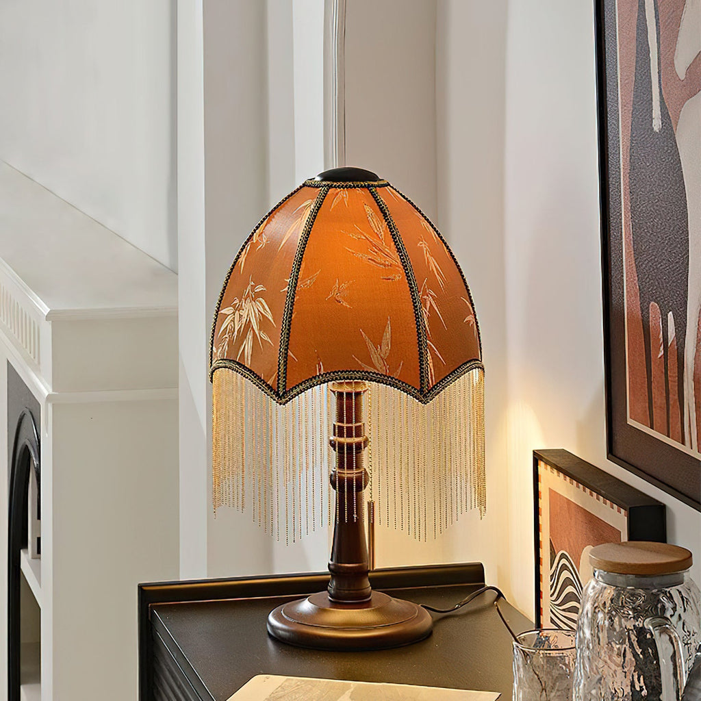 Lit on a black ribbed sideboard, this Clérachic fringe lamp glows beside a framed horse print, a glass jar and a round wooden base.