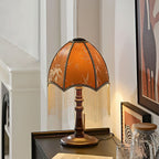 Lit on a black ribbed sideboard, this Clérachic fringe lamp glows beside a framed horse print, a glass jar and a round wooden base.