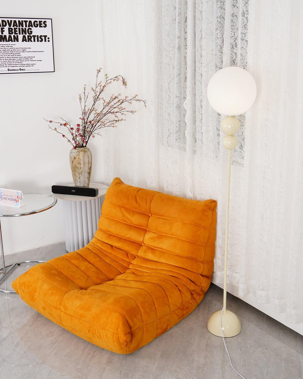 Clérachic milky white floor lamp at the shoulder of an orange lounge chair, lace curtains falling behind it.