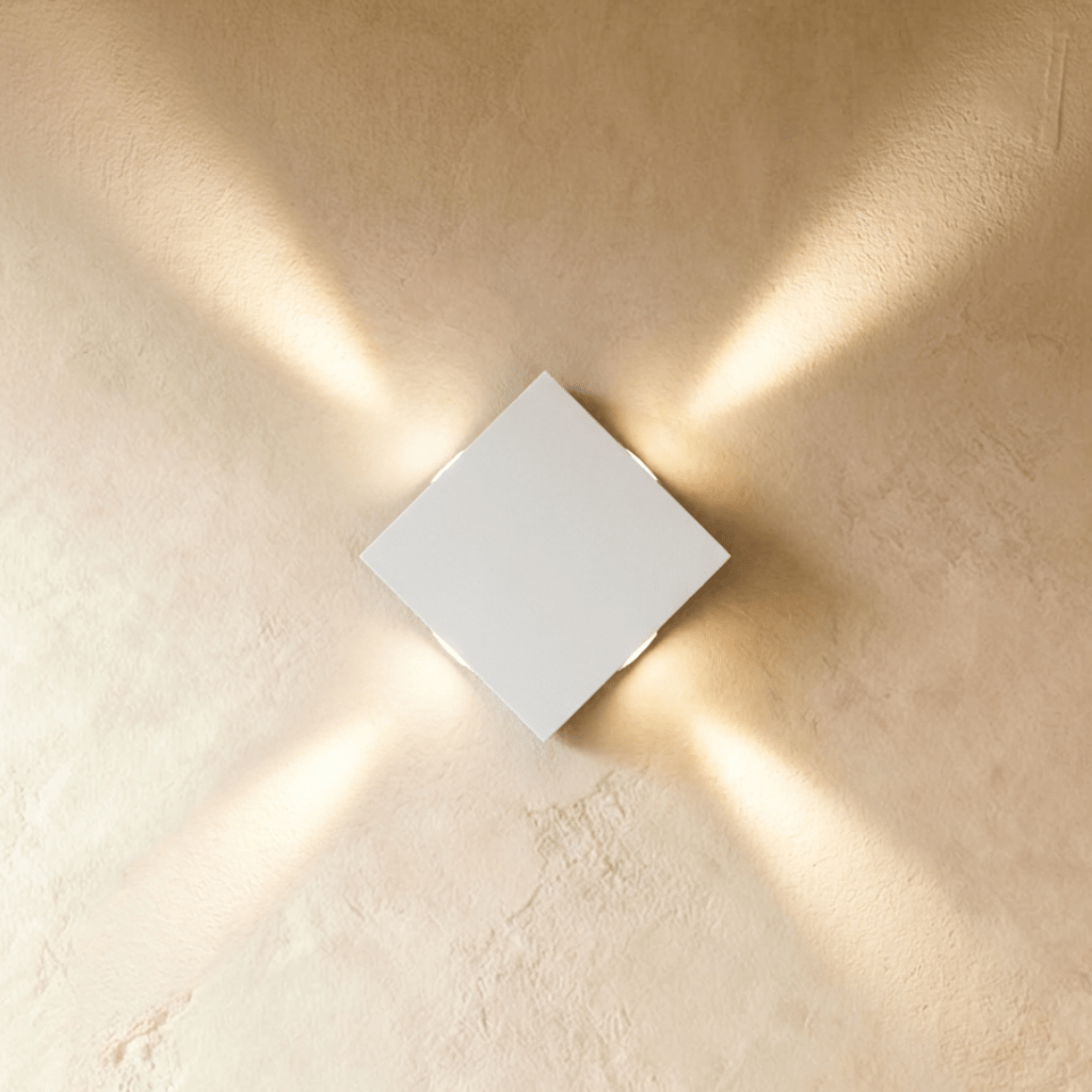 Clérachic white square wall lamp set on the diagonal, sending four slim beams of warm light to each corner.