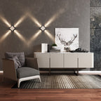 Clérachic pair of square wall lamps on a grey wall, their crossing beams forming a zigzag above a sideboard and armchair.