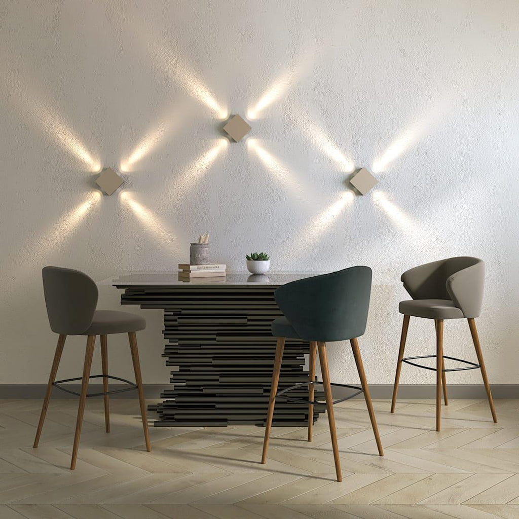 Clérachic three square wall lamps in a light finish, beams crossing the wall above a dining table and bar stools.