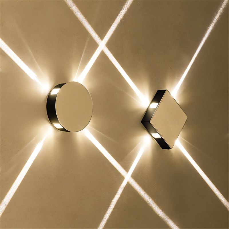 Clérachic polished metal round and square wall lamps, each shooting crossing beams of light over a warm wall.