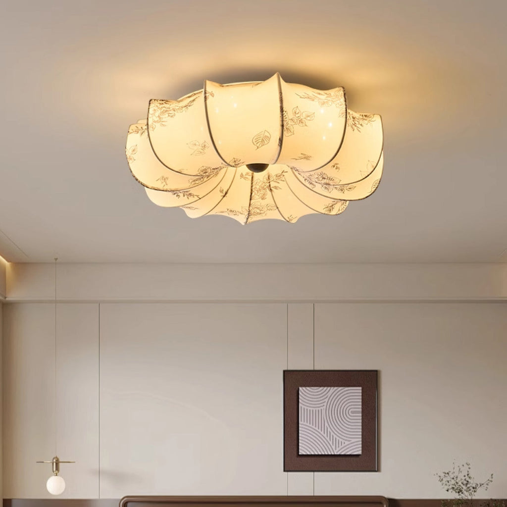 Close view from below of this Clérachic petal-shaped ceiling light, lit warm, with a floral print on the fabric panels.