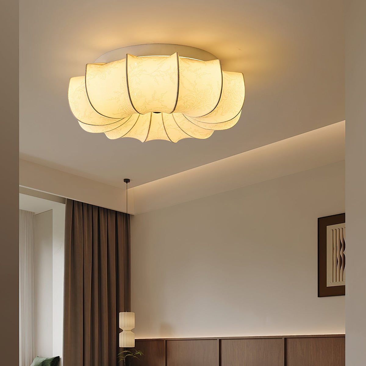 A Clérachic ceiling light glowing in a room with a cove-lit ceiling edge and brown curtains at the side.