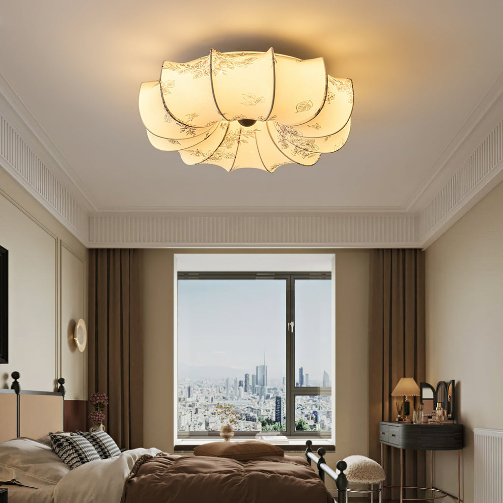 A Clérachic ceiling light glowing above a bedroom with brown bedding, a dressing table and a tall window.