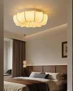 Clérachic fabric ceiling light lit above a bed with brown and grey bedding, a wood-panelled headboard wall and a framed print.